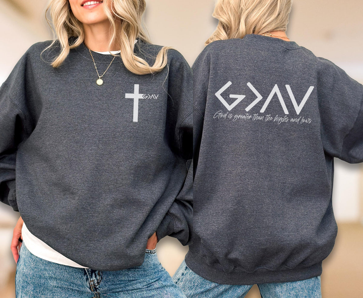 May include: A dark charcoal gray crewneck sweatshirt featuring a white cross graphic on the left chest with the text G>AV. The back displays a large white G>AV graphic with the text God is greater than the highs and lows printed below it.