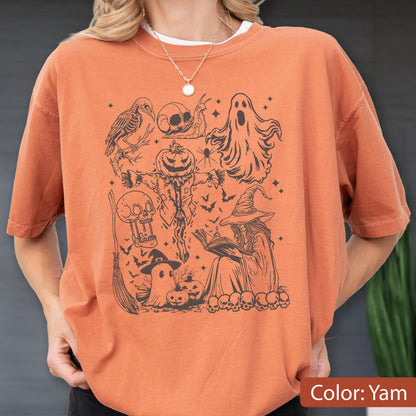 May include: Orange t-shirt with a black Halloween-themed graphic. The design includes a crow skeleton, skulls, a ghost, a scarecrow with a pumpkin head, a witch reading a book, bats, and pumpkins. The shirt's color is Yam.