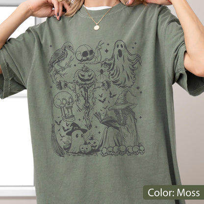 May include: Moss green t-shirt featuring a Halloween-themed graphic. The design includes a crow, skull, ghost, scarecrow, witch, bats, and pumpkins. The text "Color: Moss" is at the bottom right.