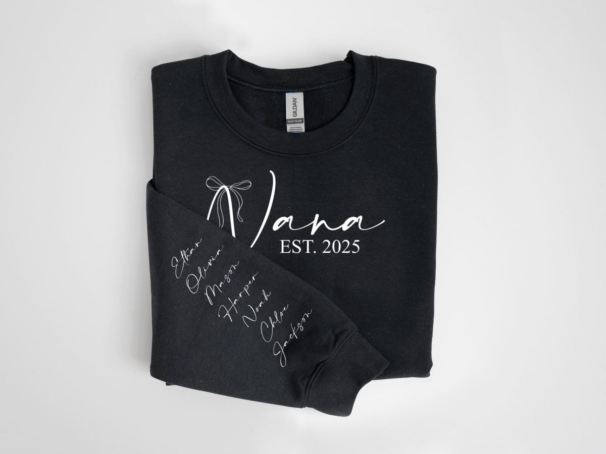 May include: Black sweatshirt with the word "Nana" in white script, a bow graphic, and the text "EST. 2025." The left sleeve displays names in white script. A cozy, casual garment.