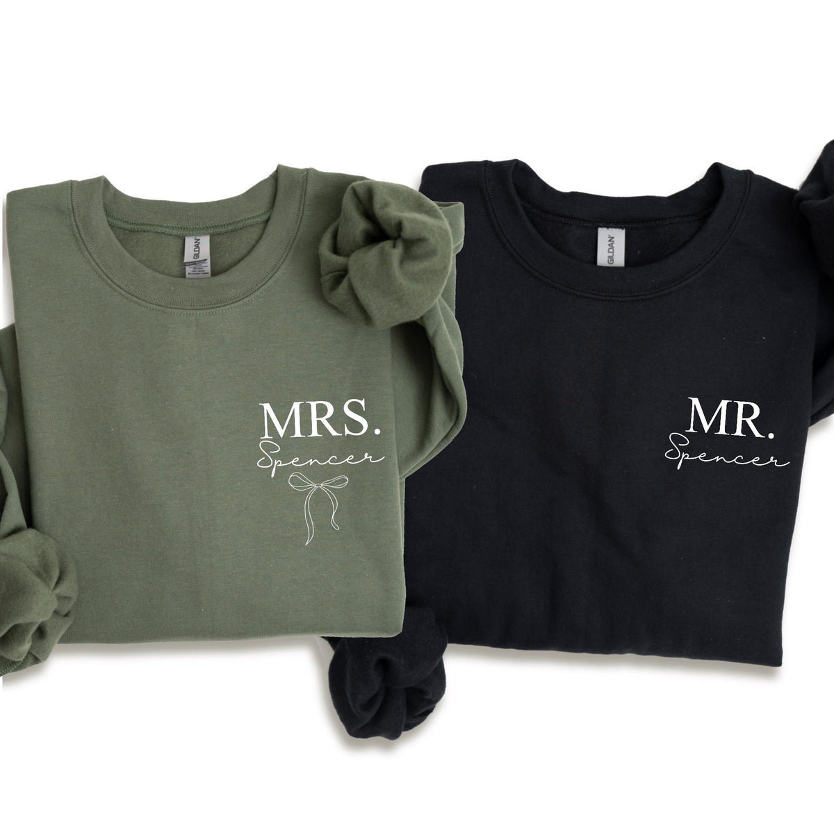 May include: Two crewneck sweatshirts, one olive green and one black. The olive green sweatshirt has the text "MRS. Spencer" with a bow graphic. The black sweatshirt has the text "MR. Spencer". Both sweatshirts are long-sleeved.