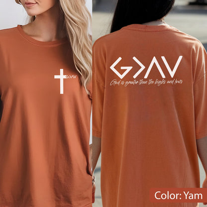 May include: A yam-colored t-shirt featuring a white cross graphic on the front left chest with the text G>AV. The back displays a large white G>AV graphic with the text God is greater than the highs and lows written in a script font.