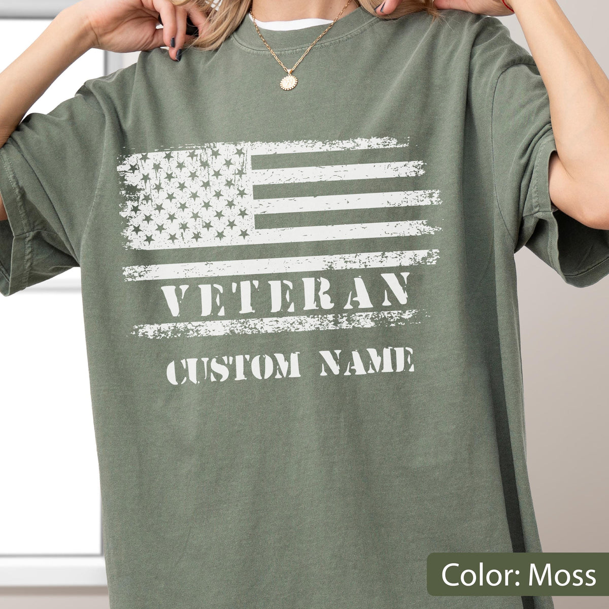 May include: A moss green t-shirt featuring a distressed white graphic of the American flag. Below the flag, the word VETERAN is printed in a bold, distressed white font, followed by the text CUSTOM NAME in the same white, weathered style.