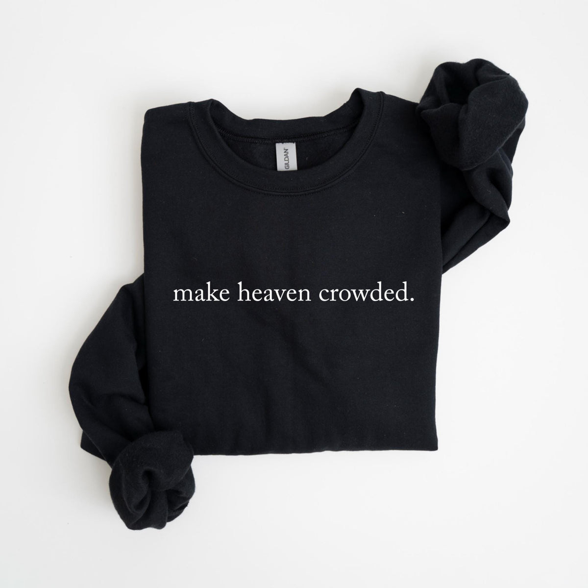 May include: Black crew neck sweatshirt with the phrase "make heaven crowded" printed in white. The long-sleeved top is folded neatly on a white surface. The Gildan brand tag is visible at the neckline.