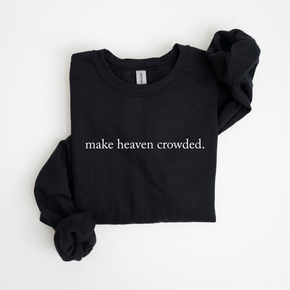 May include: Black crew neck sweatshirt with the phrase "make heaven crowded" printed in white. The long-sleeved top is folded neatly on a white surface. The Gildan brand tag is visible at the neckline.