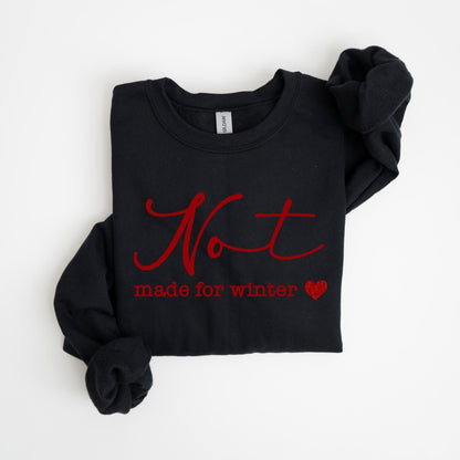 May include: Black long-sleeve sweatshirt with the red text "Not made for winter" and a red heart. The sweatshirt is folded on a white surface. The Gildan brand tag is visible.
