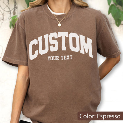 May include: Espresso-colored t-shirt with the word "CUSTOM" arched across the chest in white block letters, with "YOUR TEXT" below. The shirt has short sleeves and a crew neck.