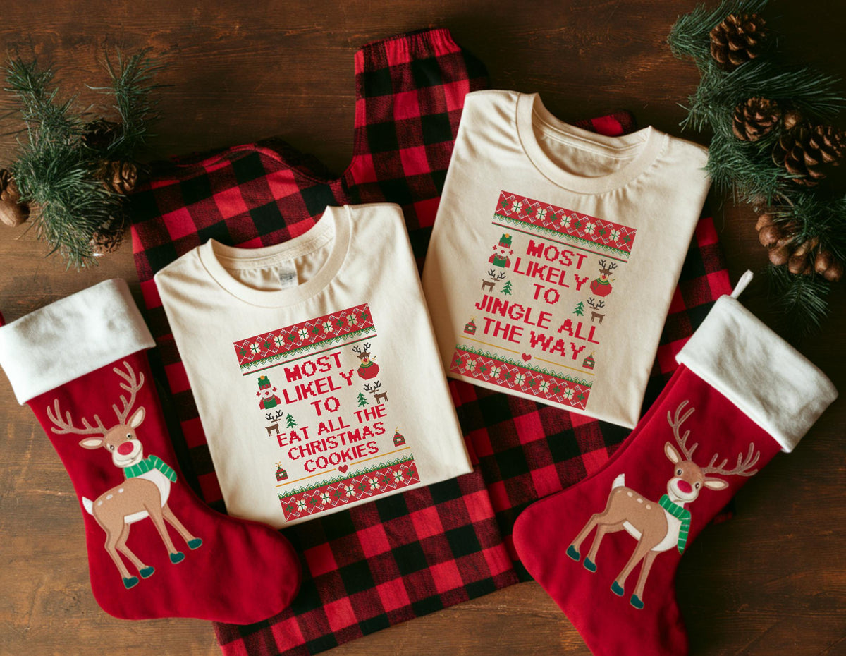 May include: Two cream-colored t-shirts with Christmas-themed text and graphics, alongside red plaid pajama pants and two red Christmas stockings with reindeer designs. The shirts read "Most Likely to Eat All the Christmas Cookies" and "Most Likely to Jingle All the Way."