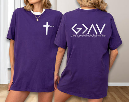 May include: Purple t-shirt with a white cross and the letters "G>AV" on the front. The back of the shirt features the text "G>AV" and the phrase "God is greater than the highs and lows" in white. The shirt has a white collar.
