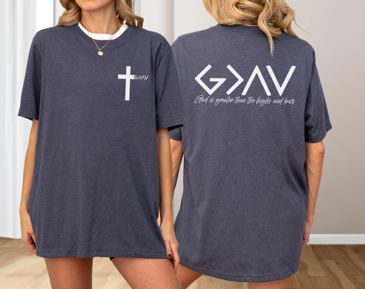 May include: Dark gray t-shirts with white text and graphics. One shirt has a white cross and the letters "G>AV" on the front. The back of the shirt has the text "G>AV" and the words "God is greater than the highs and lows."