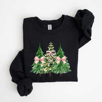 May include: Black sweatshirt featuring a watercolor design of three Christmas trees. The trees are green with pink bows, and the center tree is adorned with pink bows. The sweatshirt is folded neatly on a white surface.