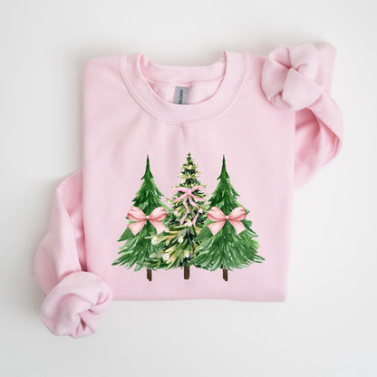 May include: A light pink sweatshirt featuring a watercolor design of three Christmas trees. The trees are green with pink bows, and the middle tree has a more detailed design. The sweatshirt is made of a soft material.