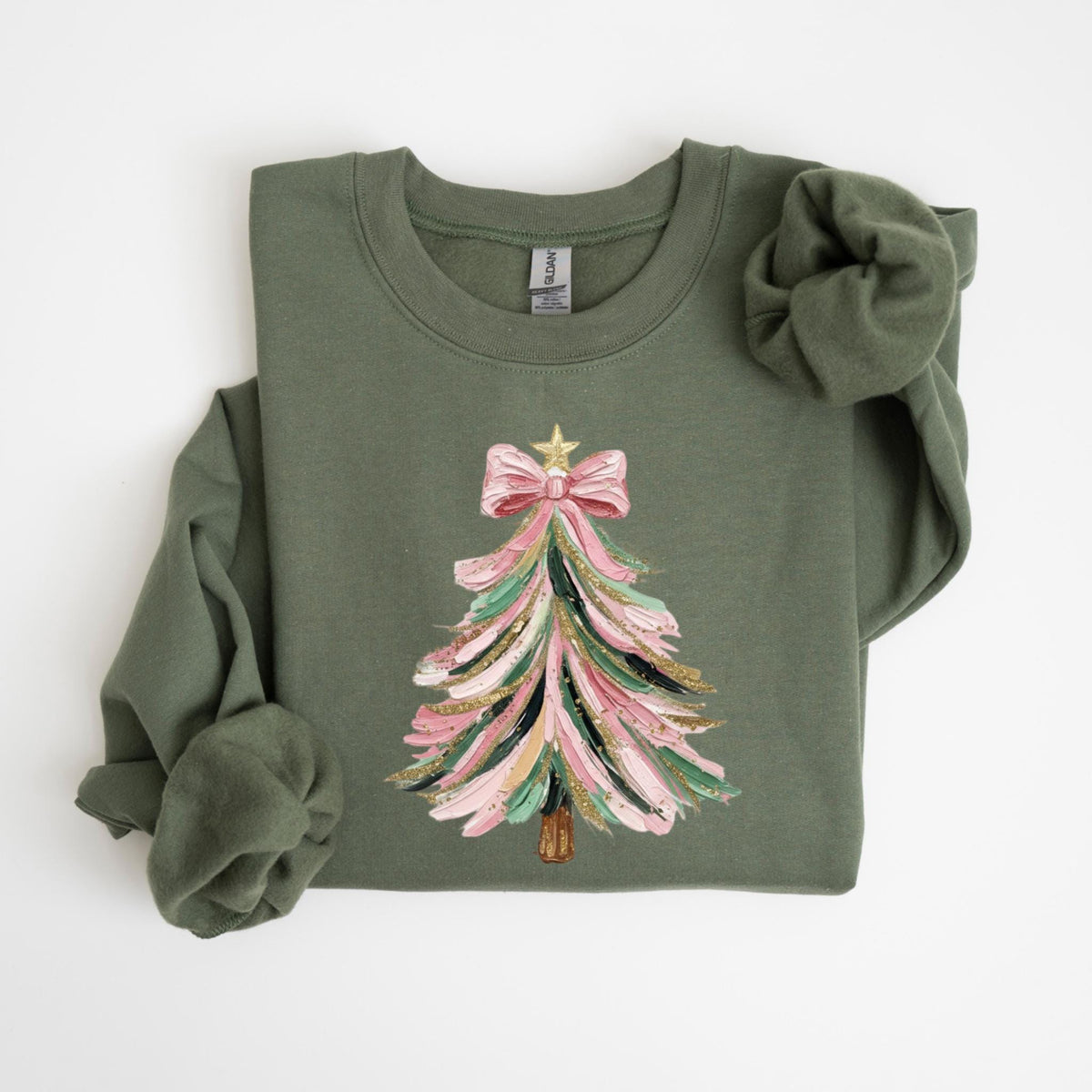 May include: An olive green sweatshirt featuring a Christmas tree design. The tree is decorated with pink, green, gold, and black brushstrokes, topped with a pink bow and a gold star. The sweatshirt is made of a soft material.
