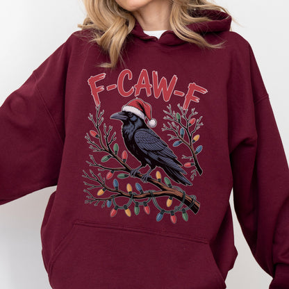 May include: A maroon hooded sweatshirt featuring a graphic of a black crow wearing a red and white Santa hat, perched on a tree branch wrapped in colorful Christmas lights. The text F-CAW-F is printed in red above the crow on the front of the garment.