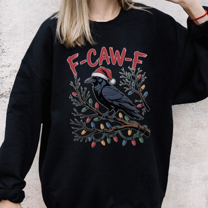 May include: A black crewneck sweatshirt featuring a graphic of a crow wearing a red and white Santa hat, perched on a branch wrapped in colorful Christmas lights. The text F-CAW-F is printed in red above the crow illustration.