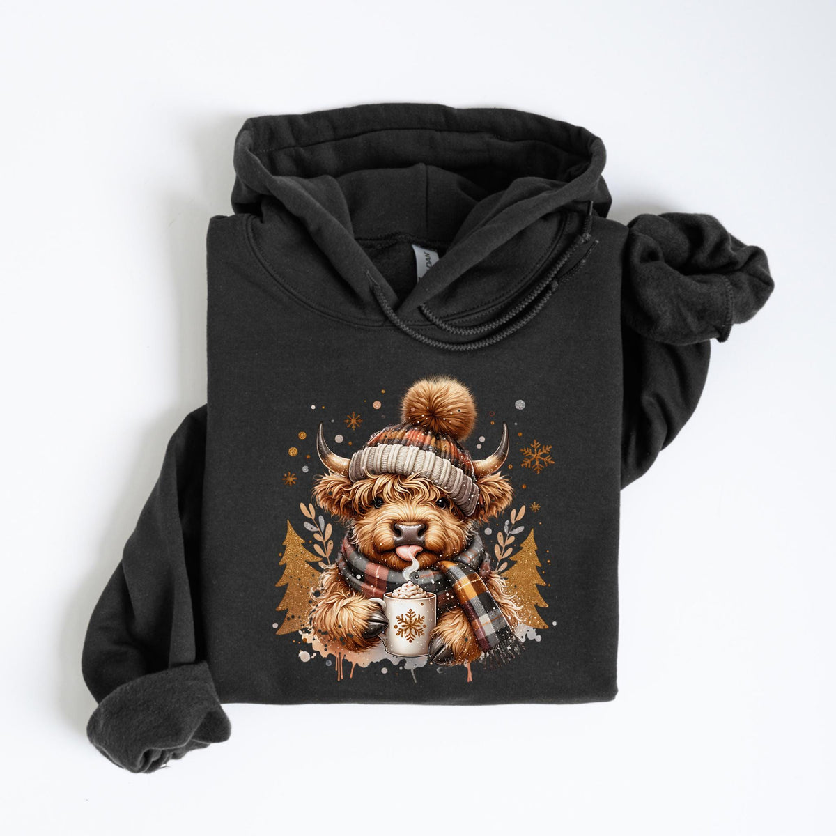 May include: Dark gray hoodie featuring a Highland cow illustration. The cow is wearing a plaid hat, scarf, and holding a mug of hot cocoa. The design includes snowflakes and pine trees, creating a cozy winter theme.