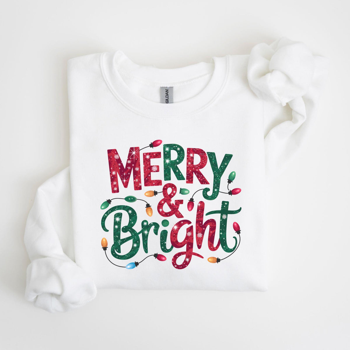 May include: White sweatshirt with the words "MERRY & Bright" in red and green lettering. The text is decorated with colorful Christmas lights. The sweatshirt is a festive holiday apparel item.