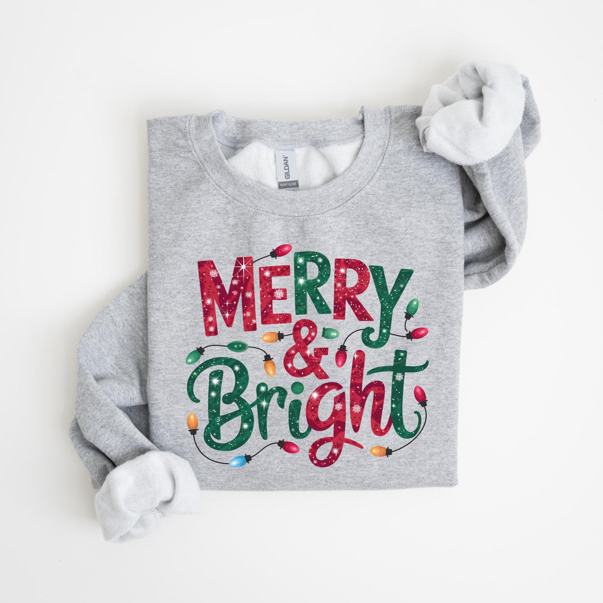 May include: A light gray sweatshirt with the words "MERRY & BRIGHT" in red and green, decorated with string lights. The sweatshirt has a crew neck and long sleeves with white lining.