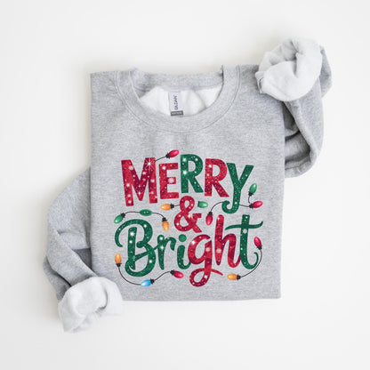 May include: A light gray sweatshirt with the words "MERRY & BRIGHT" in red and green, decorated with string lights. The sweatshirt has a crew neck and long sleeves with white lining.