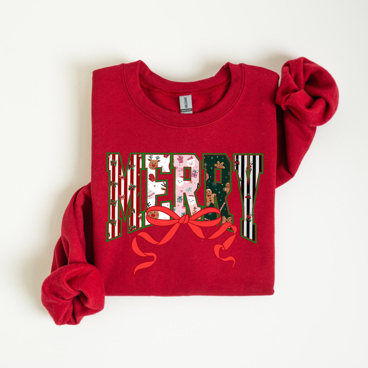 May include: A red sweatshirt with the word "MERRY" in a festive design. The letters are filled with holiday patterns, including stripes, gingerbread men, and gift boxes. A red bow is at the bottom of the word.