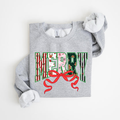 May include: A light gray sweatshirt with the word "MERRY" in a festive design. The letters are filled with holiday patterns, including reindeer, gifts, and gingerbread men. A large red bow is at the bottom of the word.