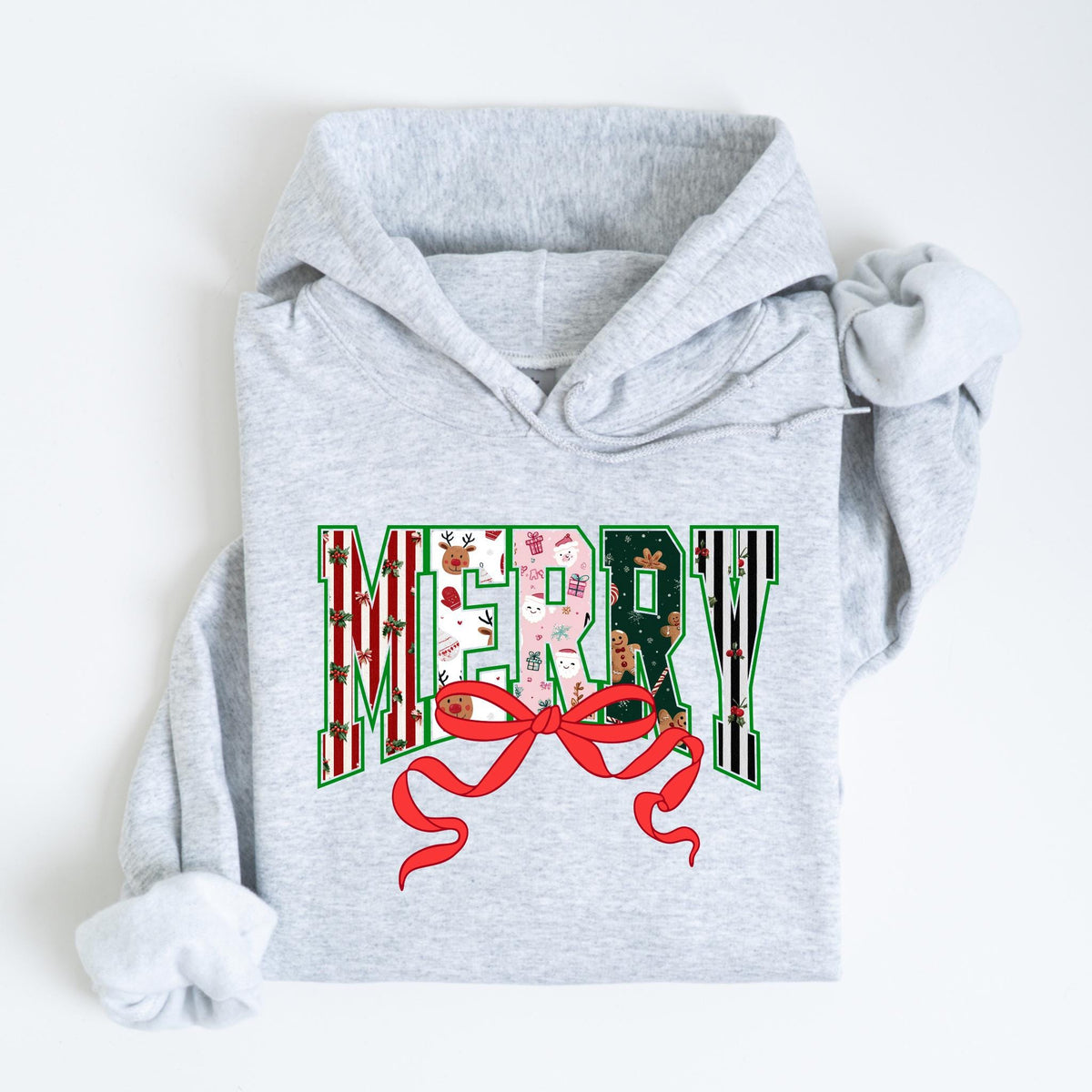 May include: A light gray hoodie with the word "MERRY" in a festive design. The letters are filled with Christmas patterns, including reindeer, snowmen, and gingerbread men. A red bow is at the bottom of the word.