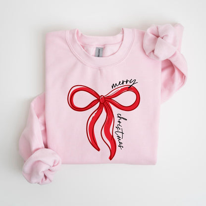 May include: A light pink sweatshirt featuring a red bow design with the words "merry christmas" in black script. The bow is a simple, elegant illustration. The sweatshirt has long sleeves and a crew neck.