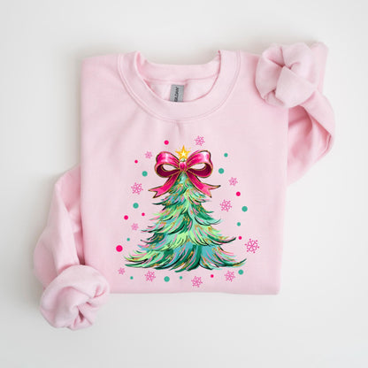 May include: A light pink sweatshirt featuring a Christmas tree design. The tree is green with blue and yellow accents, topped with a pink bow and a gold star. Pink and teal snowflakes and dots surround the tree.