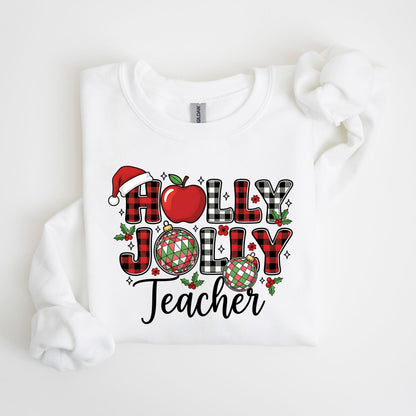 May include: White sweatshirt with a festive graphic. The design features the words "HOLLY JOLLY Teacher" in a mix of red and black plaid letters, a Santa hat, a red apple, and Christmas ornaments. The overall theme is holiday-themed.