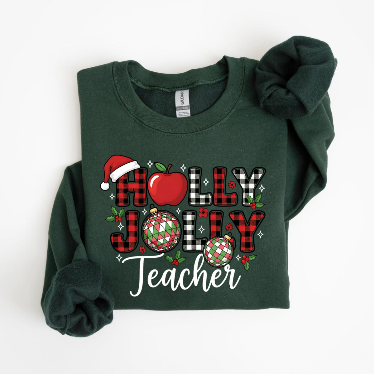 May include: Dark green sweatshirt with the words "HOLLY JOLLY Teacher" in a festive design. The design includes a red apple, Santa hat, and ornaments. The letters are red and black plaid.