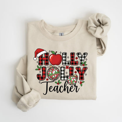 May include: Beige sweatshirt with the words "HOLLY JOLLY Teacher" in a festive design. The letters are a mix of red and black buffalo plaid, with a Santa hat, apple, and Christmas ornaments. The sweatshirt has long sleeves and a crew neck.