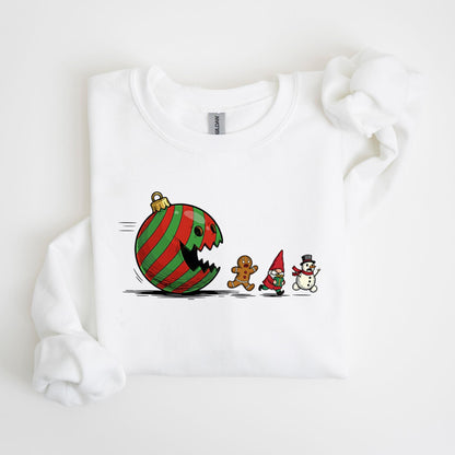 May include: White sweatshirt featuring a cartoon design of a red and green striped Christmas ornament chasing a gingerbread man, a gnome, and a snowman. The design is a playful take on a holiday theme.