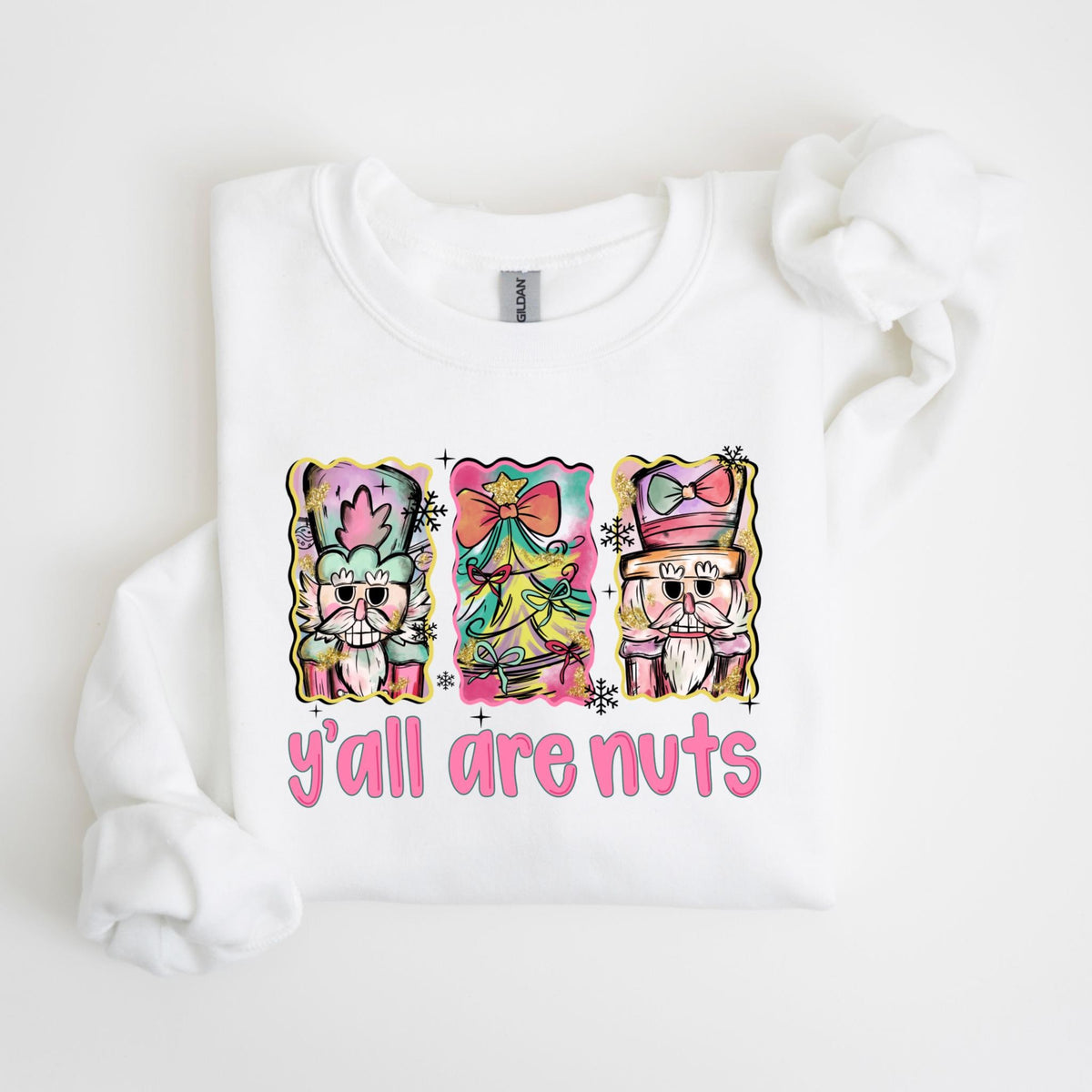 May include: White sweatshirt with a colorful graphic of three nutcrackers and the text "y'all are nuts" in pink. The nutcrackers have ornate hats and beards, with a Christmas tree in the center.