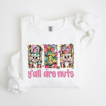 May include: White sweatshirt with a colorful graphic of three nutcrackers and the text "y'all are nuts" in pink. The nutcrackers have ornate hats and beards, with a Christmas tree in the center.