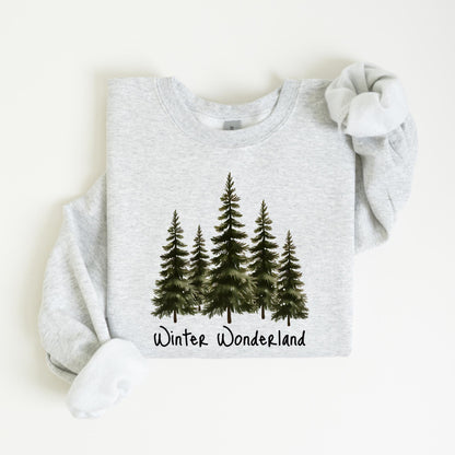 May include: A light gray sweatshirt featuring a watercolor design of five evergreen trees. Below the trees is the text "Winter Wonderland" in a handwritten style. The sweatshirt has a crew neck and long sleeves.
