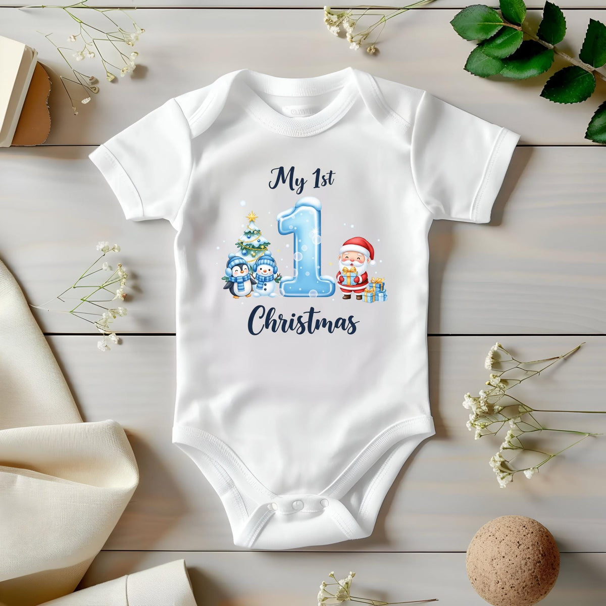May include: White baby onesie with a Christmas theme. The onesie features the text "My 1st Christmas" with a blue number 1, a Christmas tree, penguins, and Santa Claus.