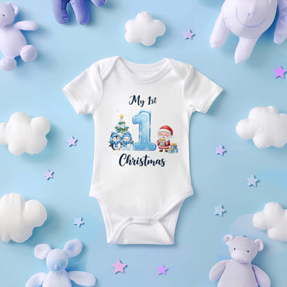 May include: White baby onesie with a festive Christmas design. The onesie features the text "My 1st Christmas" with a large number 1, penguins, a Christmas tree, and Santa Claus. The onesie is surrounded by plush toys and star-shaped decorations.