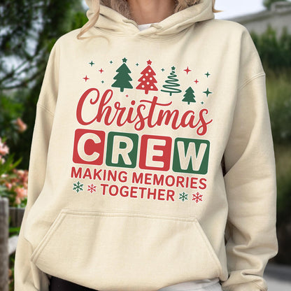 May include: A cream-colored hooded sweatshirt featuring a graphic print with red and green Christmas trees, stars, and snowflakes. The text reads "Christmas CREW" in red and green, followed by "MAKING MEMORIES TOGETHER" in red block letters.