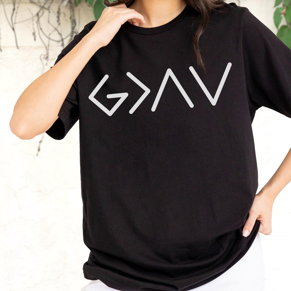 May include: A black short-sleeved t-shirt featuring a white graphic print on the chest. The design consists of the mathematical symbols G > I V, which are arranged in a stylized, linear font across the center of the garment.