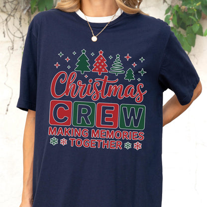 May include: A navy blue short-sleeve t-shirt featuring a graphic print with red and green Christmas trees, stars, and snowflakes. The text reads "Christmas CREW" in large block letters, followed by "MAKING MEMORIES TOGETHER" in red.