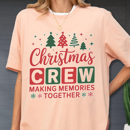 May include: A peach-colored t-shirt featuring a graphic with red and green Christmas trees, stars, and the text "Christmas CREW MAKING MEMORIES TOGETHER" in red and green block lettering, accented with small snowflake icons at the bottom.