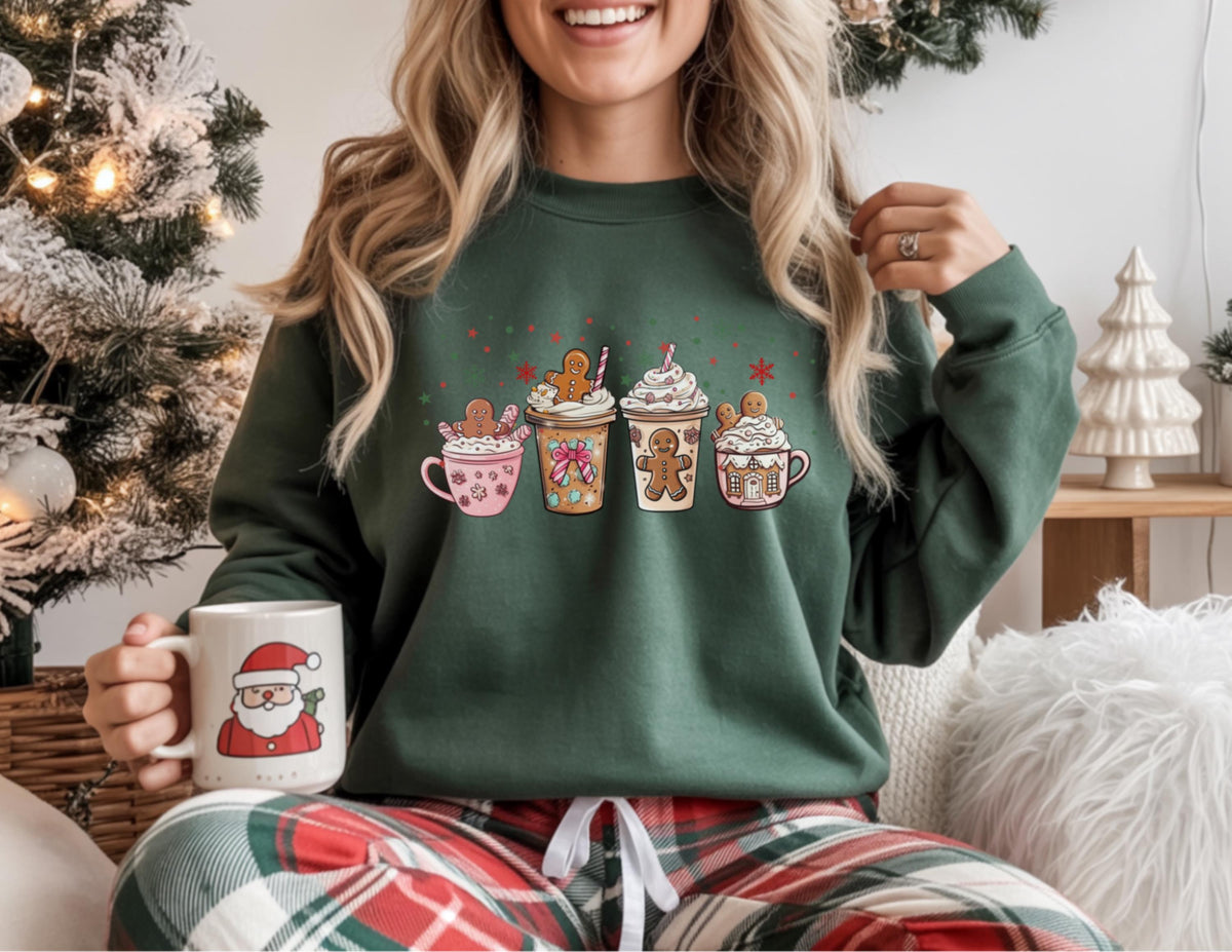 May include: A dark green sweatshirt featuring a festive design of gingerbread people and whipped cream drinks. The sweatshirt has a crew neck and long sleeves. A white mug with a Santa Claus graphic is held in the hand.