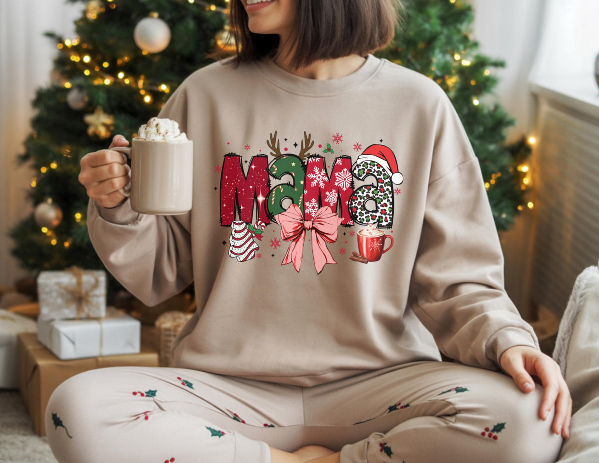 May include: Beige sweatshirt with the word "Mama" in a Christmas-themed design. The letters are decorated with red, green, and leopard print patterns, a bow, and a Santa hat. A mug of whipped cream is held in the hand.