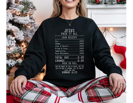 May include: Black sweatshirt with the text "JESUS PAID IT ALL" in white. The design resembles a cash receipt, listing sins and marking them as "PAID." The bottom of the shirt includes a Bible verse from Romans 6:23.