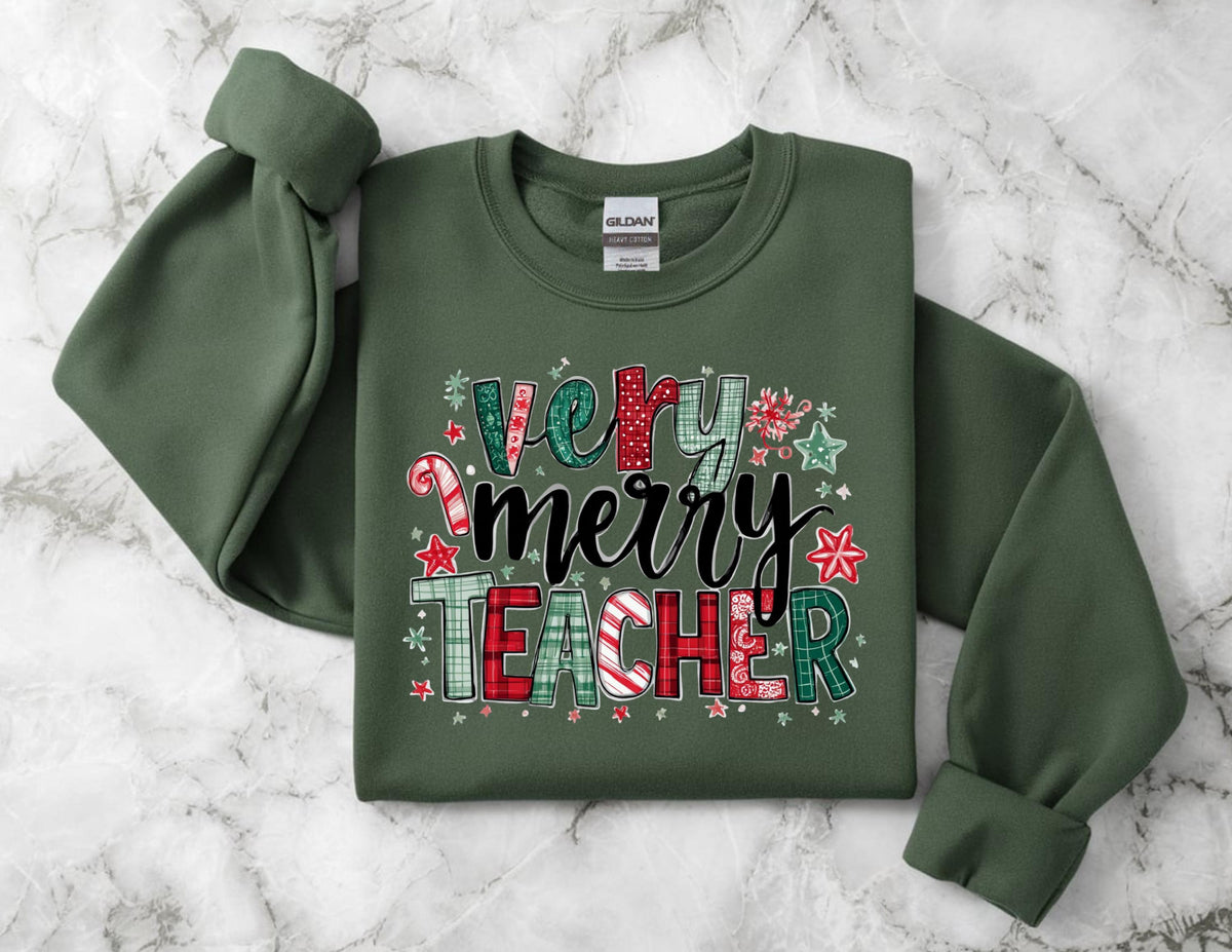 May include: An olive green sweatshirt with the words "Very Merry Teacher" in a festive design. The text features a mix of patterns, including plaid, candy canes, and stars, in red, green, and white. The sweatshirt has a crew neck and long sleeves.