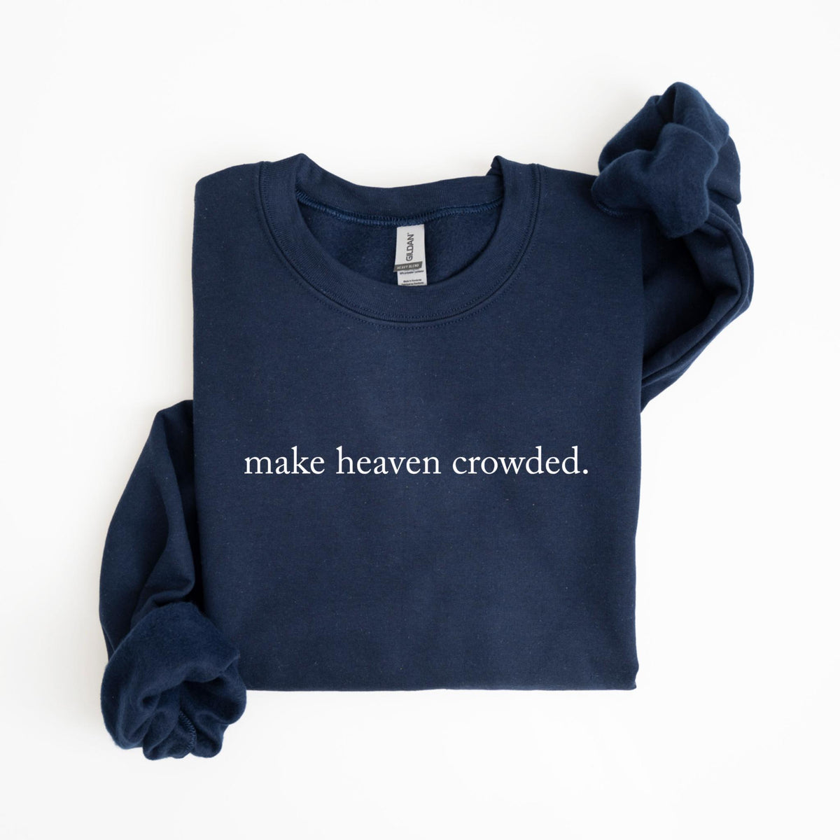 May include: A navy blue sweatshirt with the phrase "make heaven crowded." printed in white. The sweatshirt is folded, with one sleeve casually draped over the top. The Gildan brand tag is visible at the neckline.
