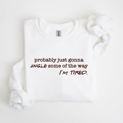 May include: White crew neck sweatshirt with the text "probably just gonna jingle some of the way I'm tired" in brown lettering. The sweatshirt is folded with the sleeves and collar visible.