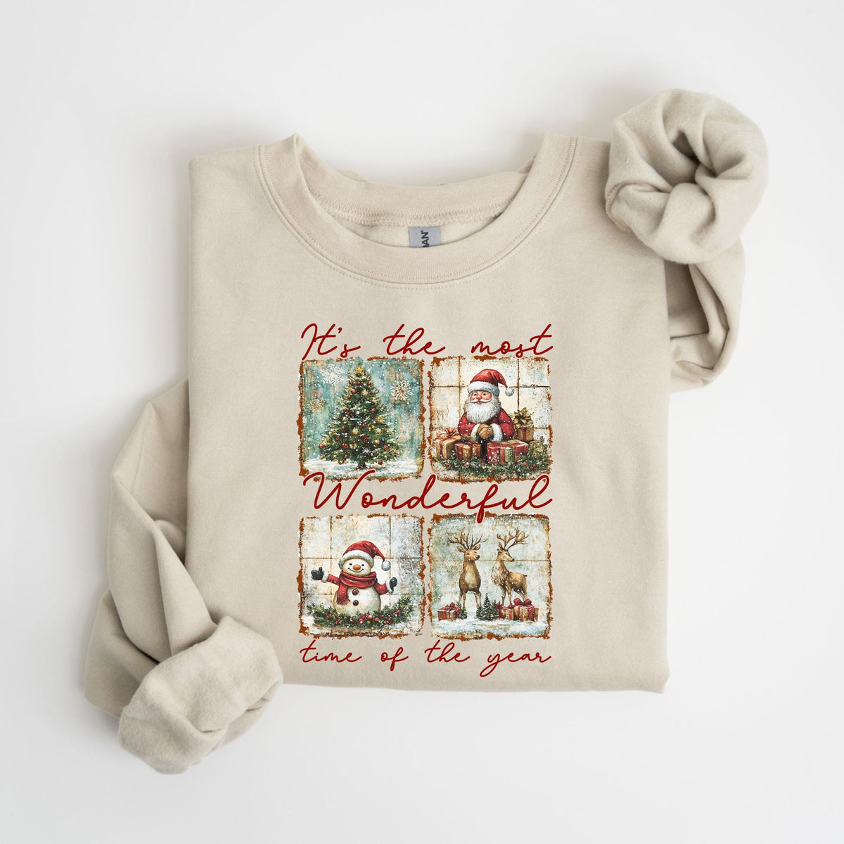 May include: Beige sweatshirt with a festive Christmas design. The design features four squares with a Christmas tree, Santa Claus, a snowman, and reindeer. The text "It's the most Wonderful time of the year" is printed in red.