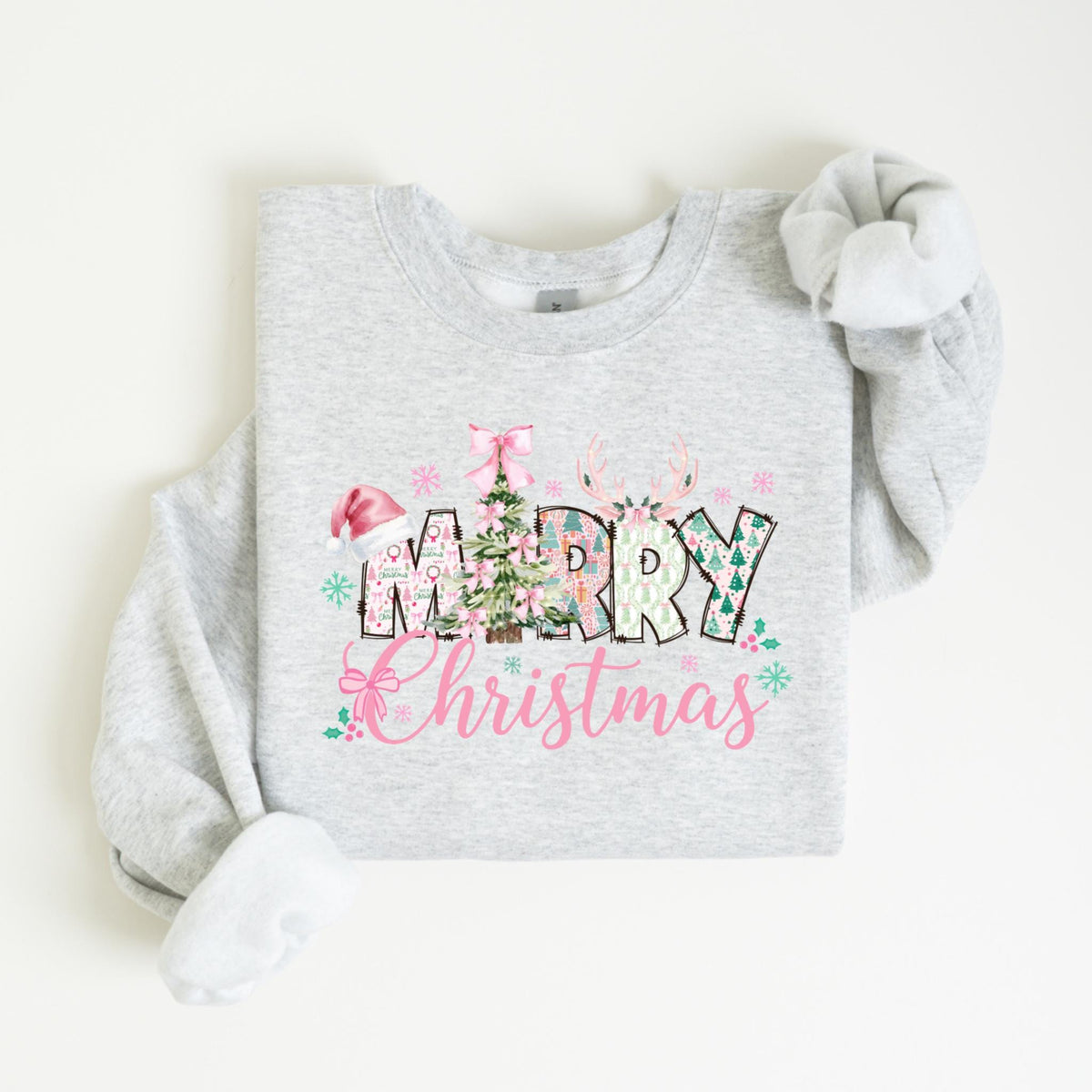 May include: A light gray sweatshirt with a festive "Merry Christmas" design. The design features a Christmas tree, reindeer antlers, and the words "Merry Christmas" in a mix of fonts and colors, including pink and green.