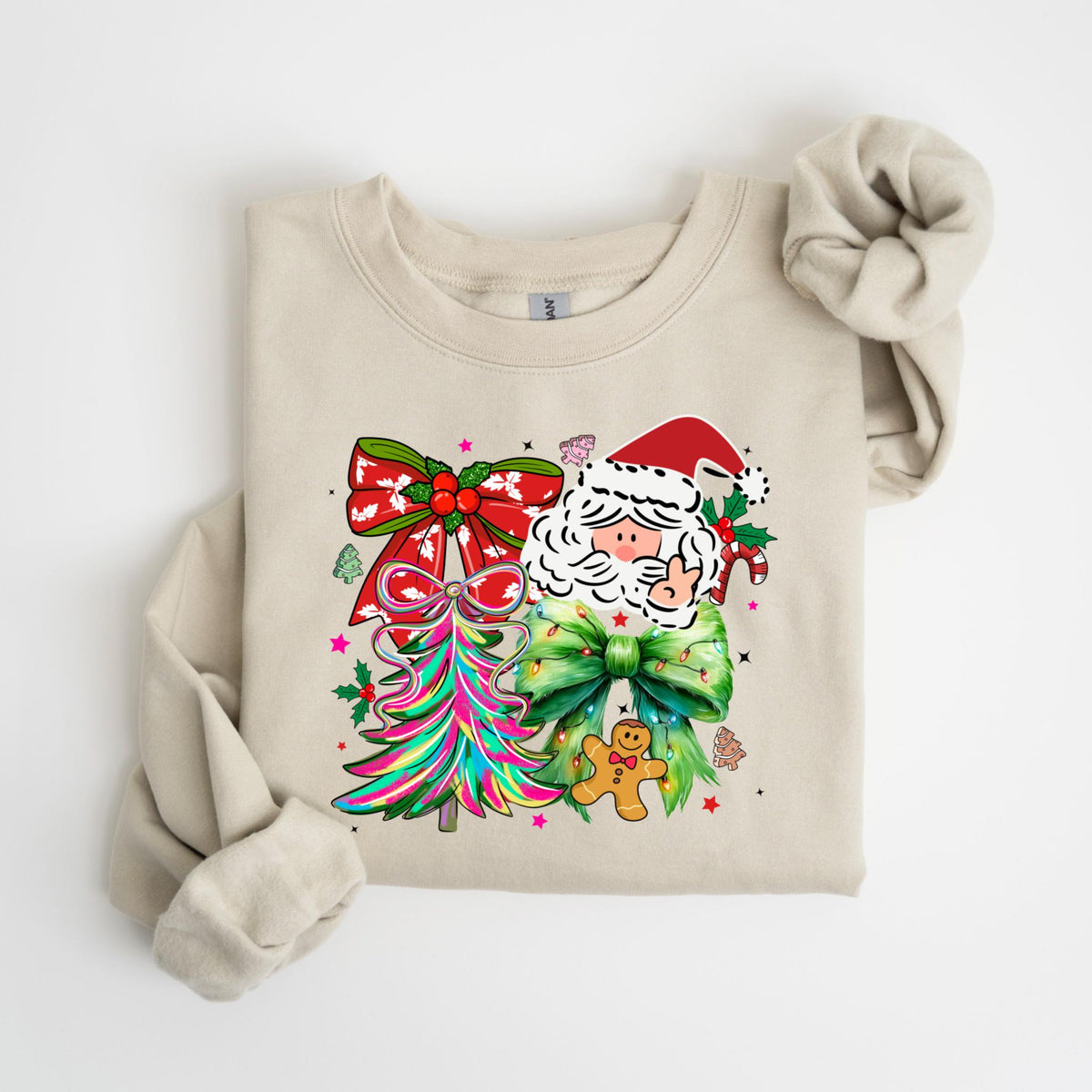 May include: Beige sweatshirt featuring a colorful Christmas design. The graphic includes Santa Claus, a Christmas tree, and bows in red, green, and pink. A gingerbread man and holly complete the festive look.